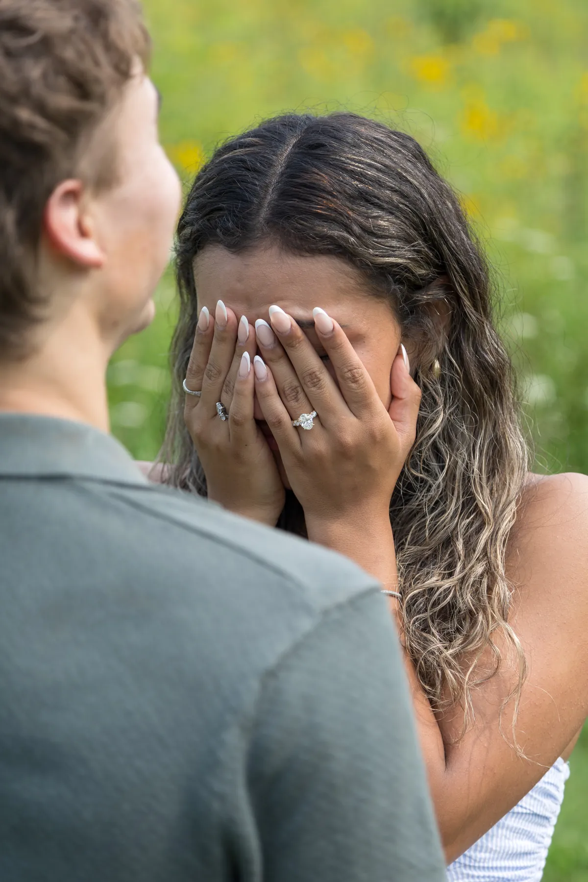 A woman covering her face in happy tears after the proposal