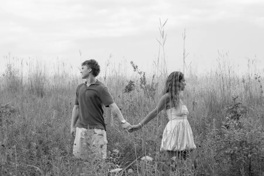 Black and white wide shot of a couple walking through tall grass