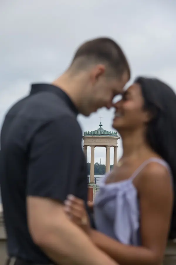 A couple forehead to forehead beside a lakeside gazebo