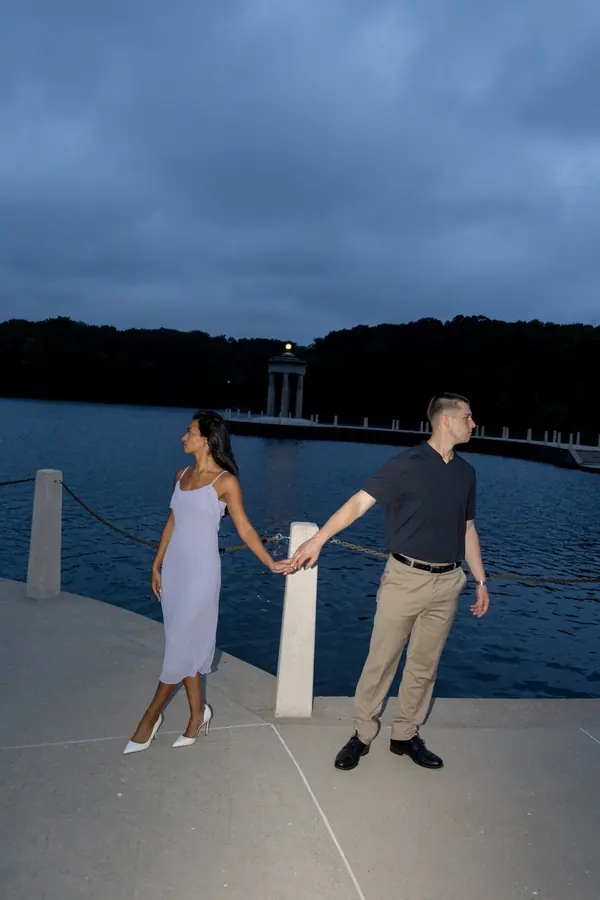 A couple holding hands on a lakeside pier at blue hour
