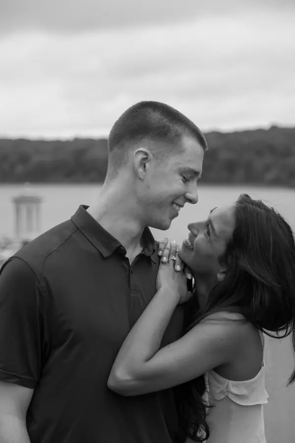 Black and white portrait of a couple smiling at each other by the lake