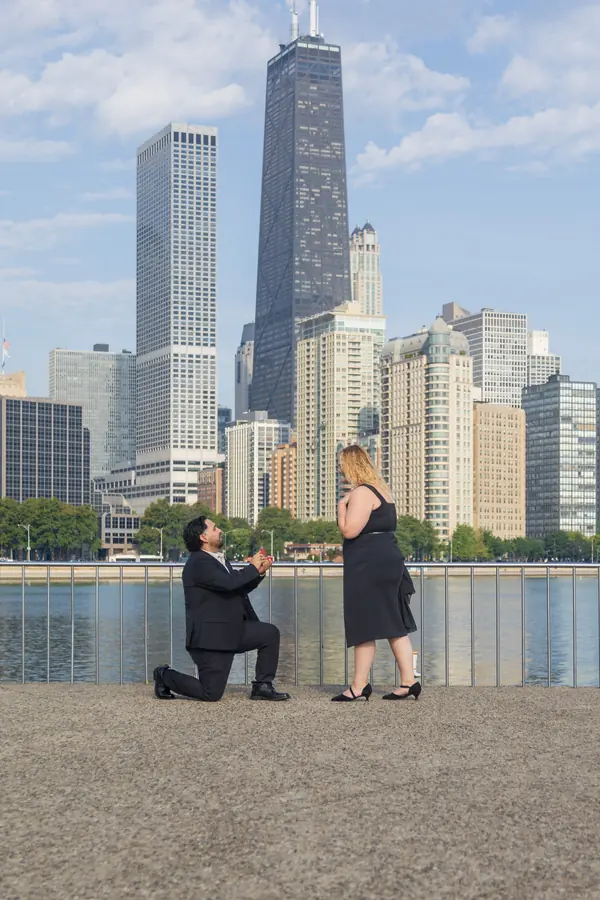A proposal on the lakefront with the Chicago skyline behind the couple