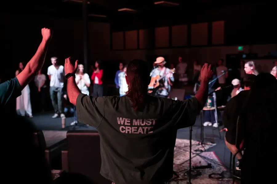A man in the crowd with his arms raised at a live music night