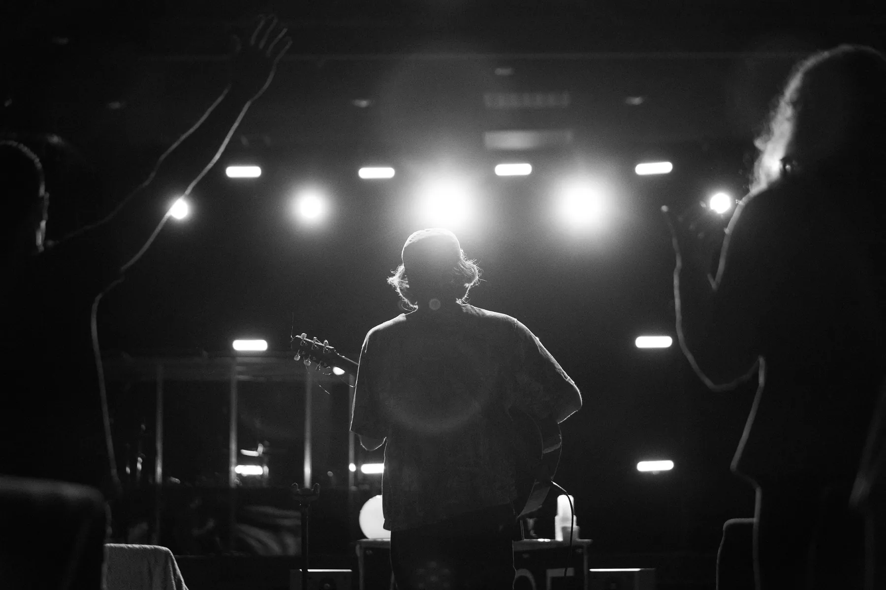 Black and white stage lights over a performer and crowd