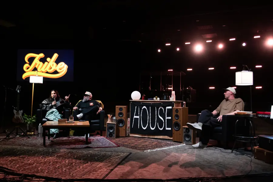 A live talk show set with a neon sign, sofas and guests