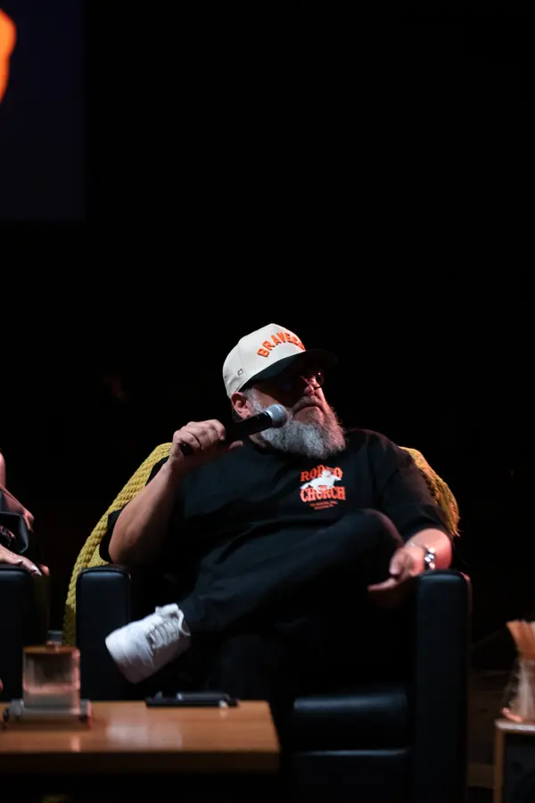 A guest holding a microphone on a dim stage