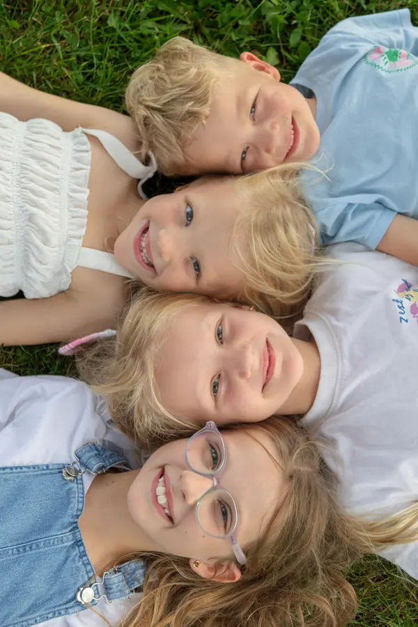 Four children lying head to head in the grass, smiling up