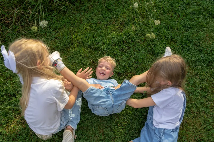 Three children tumbling together on the lawn