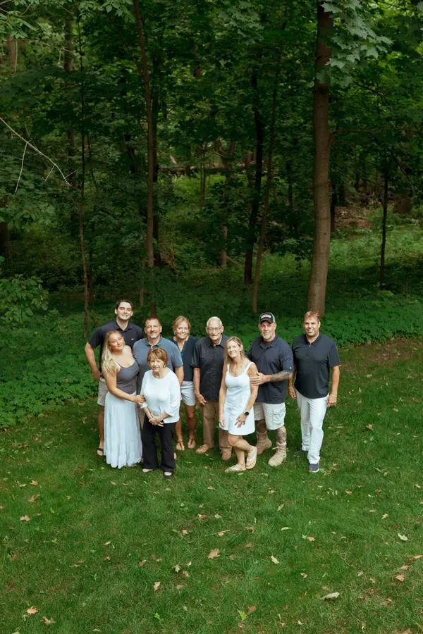 An extended family gathered beneath tall trees