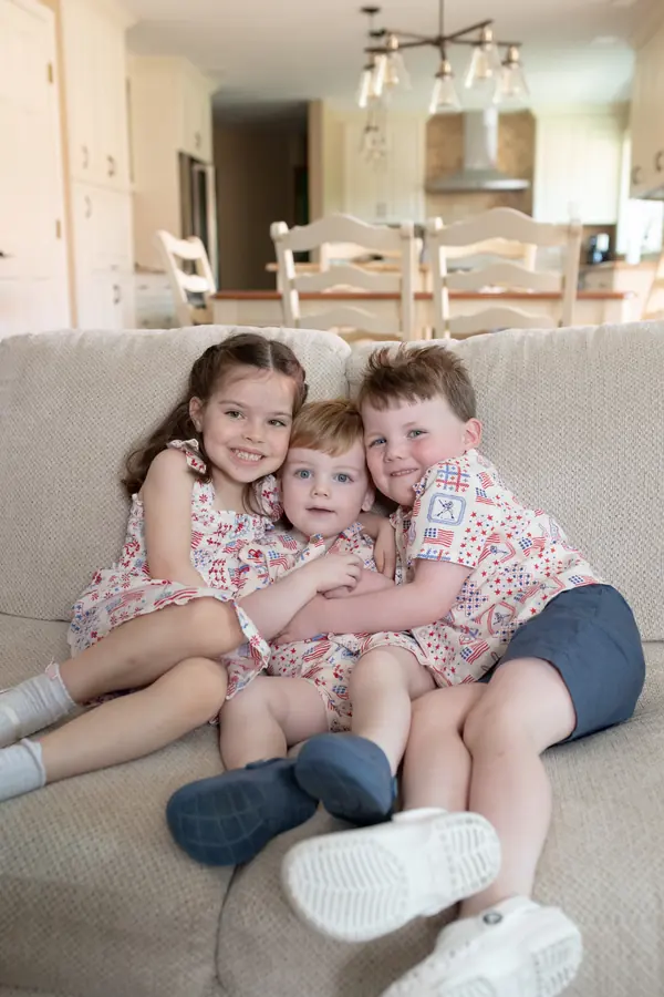 Siblings cuddled together on the sofa at home