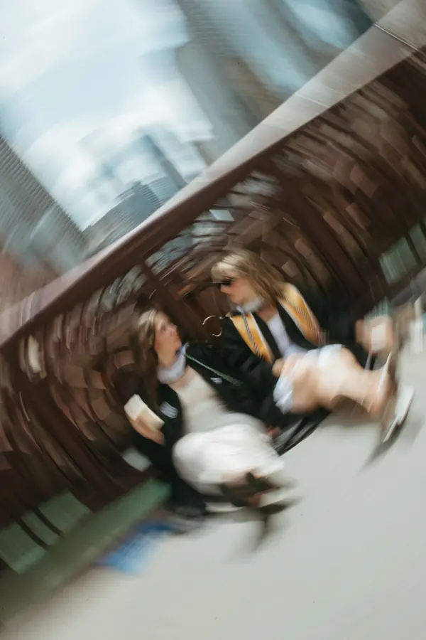 A spinning motion shot of two graduates on a bridge