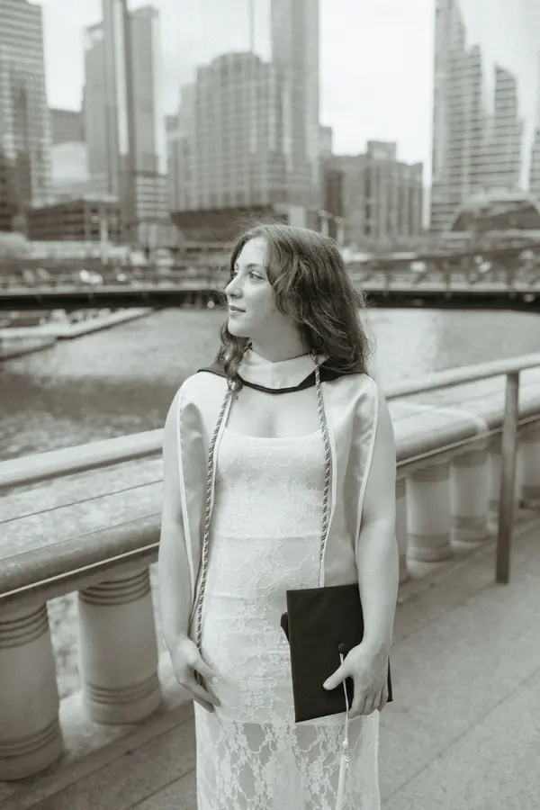 Black and white graduate in a lace dress looking over the river