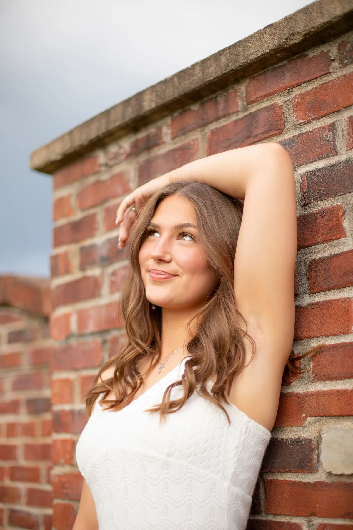 A senior leaning against a brick wall
