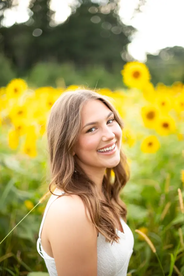 A senior laughing in front of sunflowers