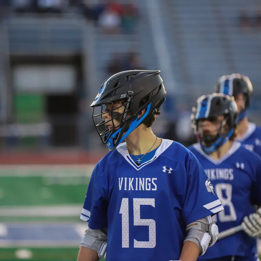 A lacrosse player in a Vikings jersey on the sideline