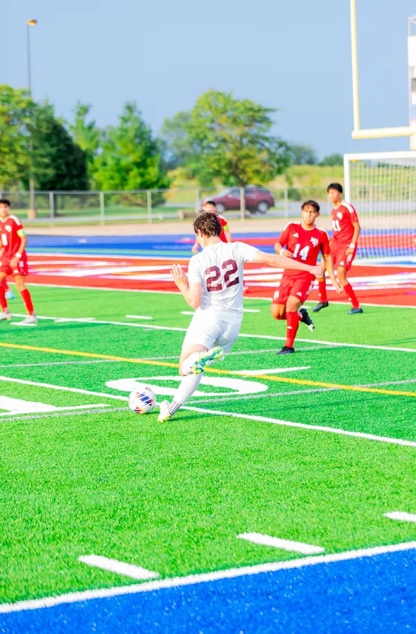 A soccer player striking the ball on a turf field