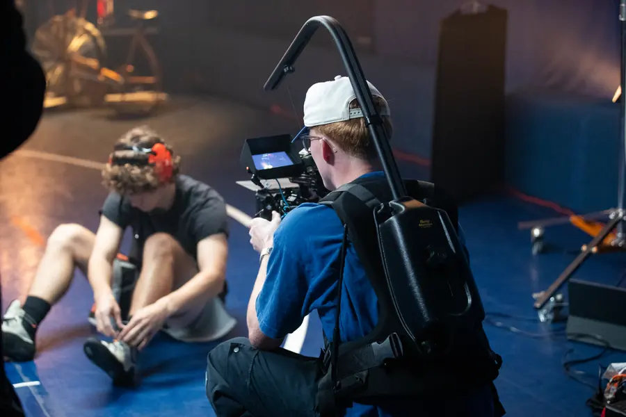 A videographer filming an athlete stretching on the mat