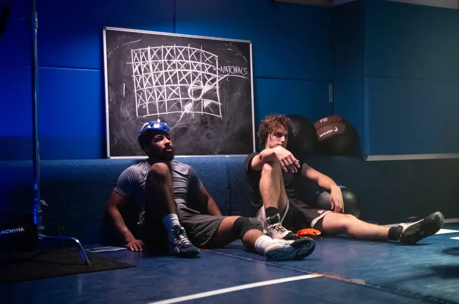 Two athletes resting on the mat between takes