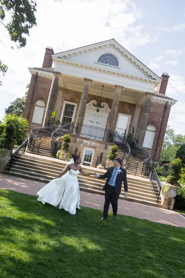 A couple on the lawn in front of a historic estate house
