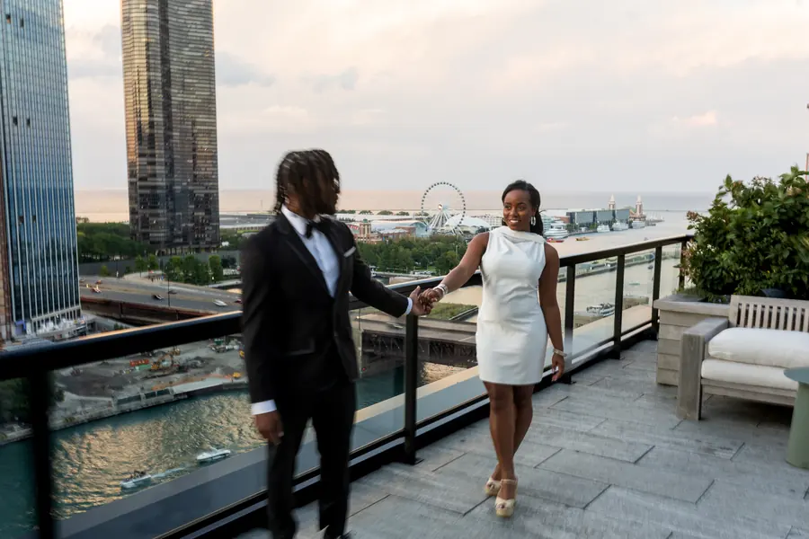 A couple holding hands on a rooftop overlooking Navy Pier