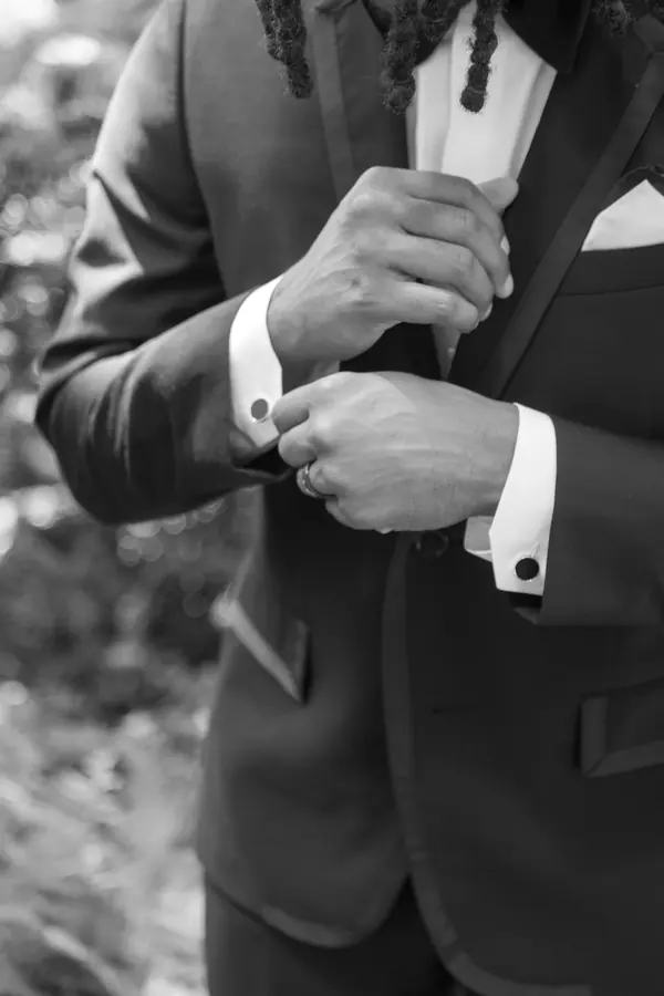 Black and white detail of a groom fixing his cufflink