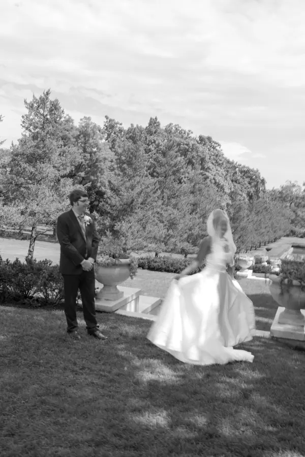 Black and white: the bride mid turn on the lawn, skirt swinging wide