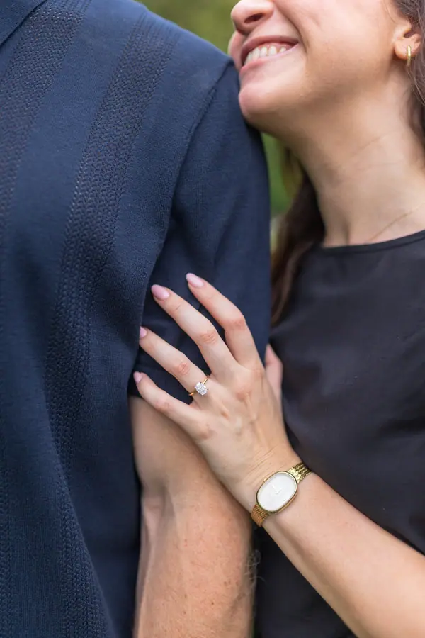Her laughing into his shoulder, her hand on his arm, ring showing