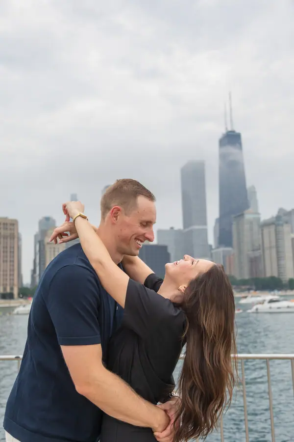 Holding each other on the breakwater, the Hancock tower over her shoulder