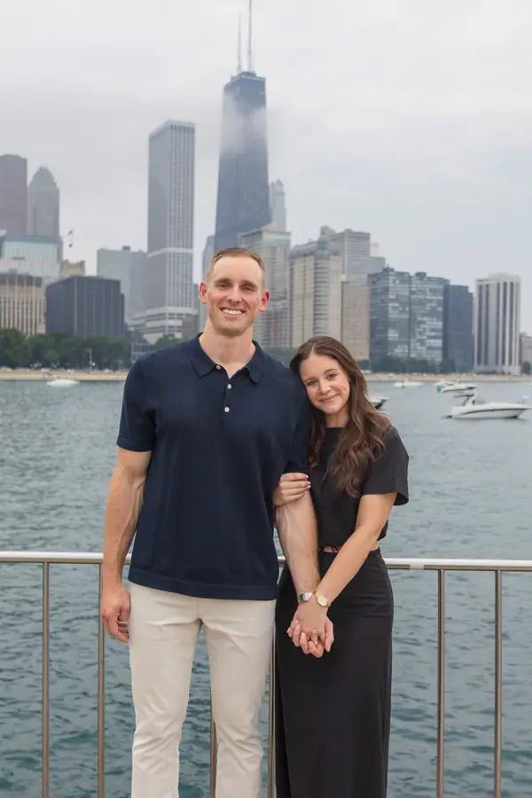 The couple standing together at the railing, the lake flat and gray behind them