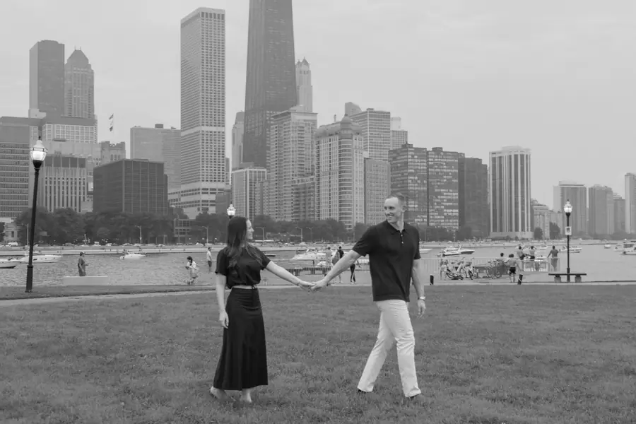 Black and white: the two of them on the grass, the city small in the distance