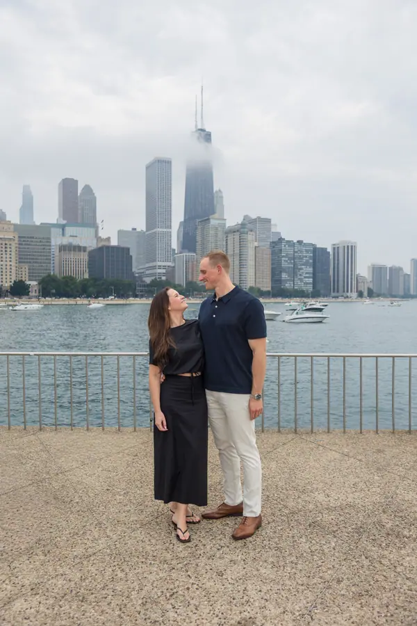 The couple on the pebble path by the water, boats moored out in the harbor