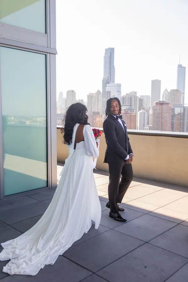 The couple on the stone steps of the city hall building, her bouquet held low
