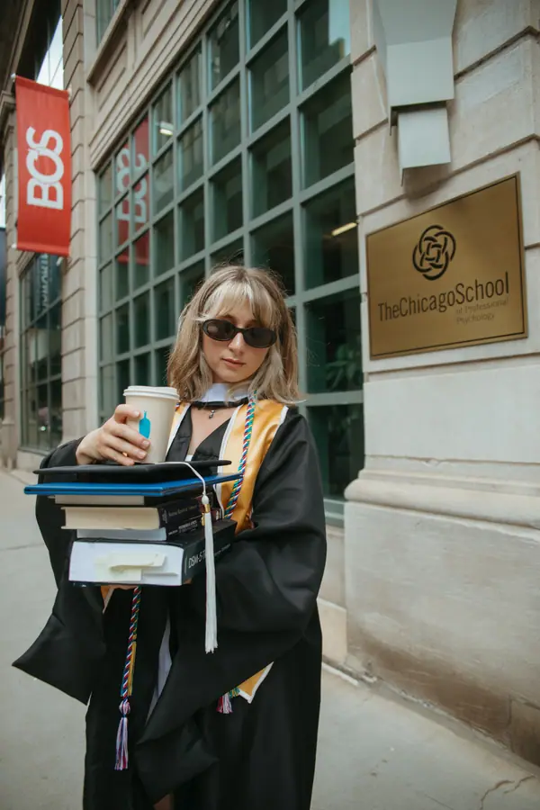 Outside the school door with her diploma folder, hand on the brass handle