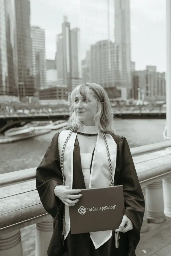 Black and white: the graduate looking down at her diploma folder on the bridge