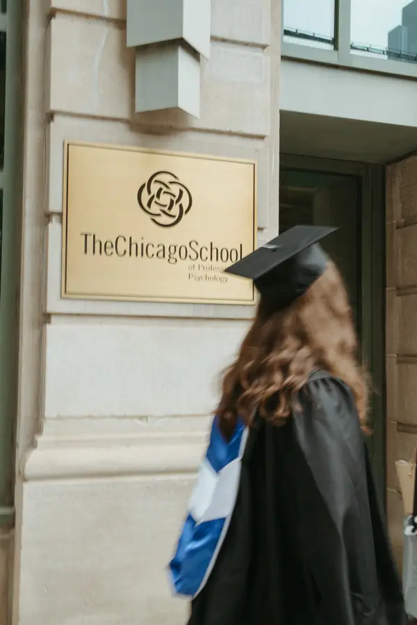 The back of her gown and hood framed against the school's entrance