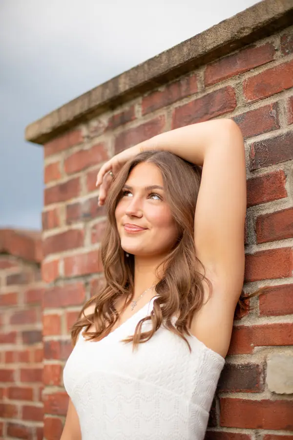 Against a red brick wall, one arm up, the light raking across the brick