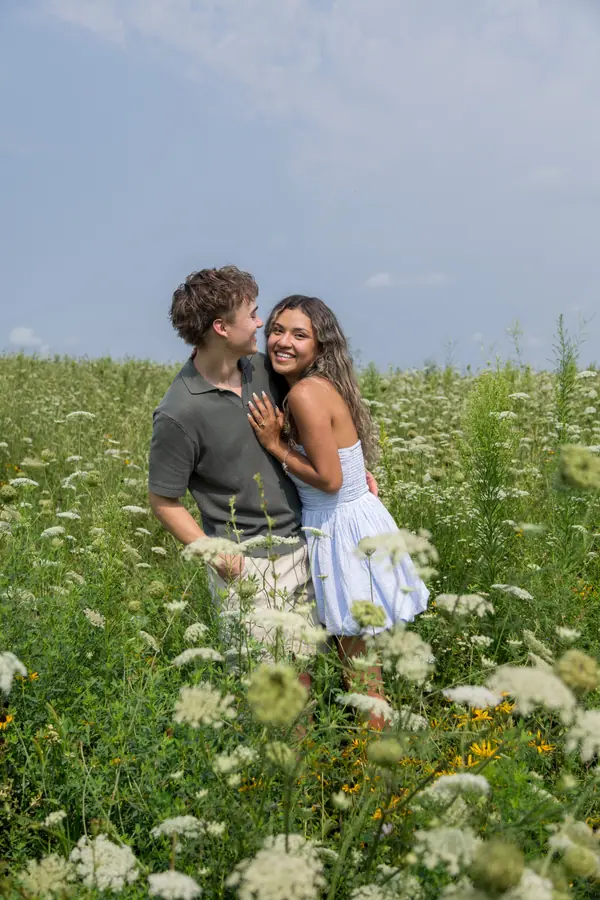 The couple standing in waist high Queen Anne's lace, arms around each other