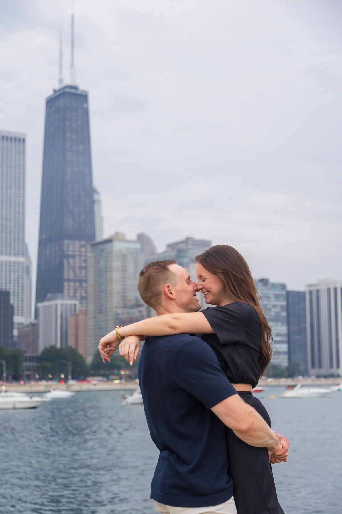 A couple holding each other on the Chicago lakefront with the skyline soft behind them