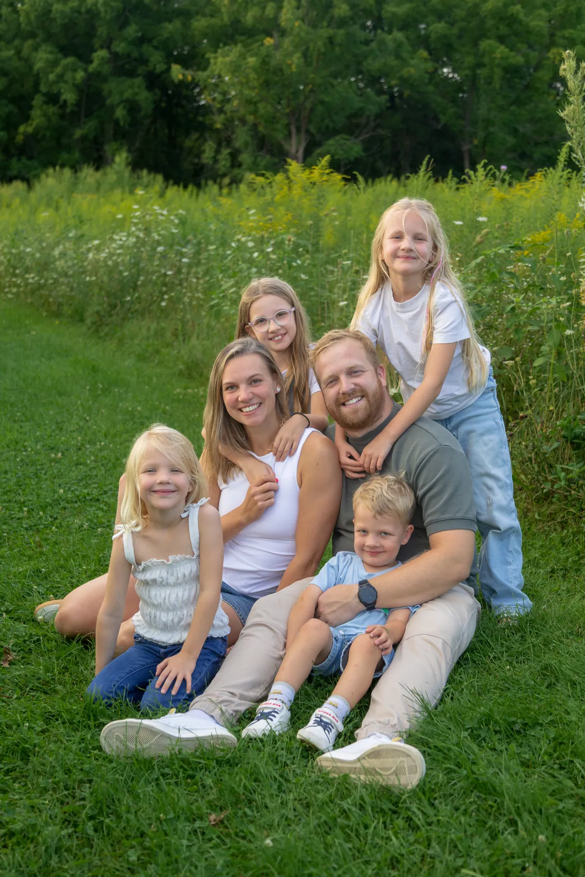 A family sitting together in a summer meadow in the late evening light